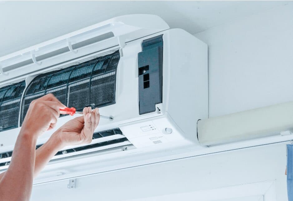 Hands opening the cover of a wall-mounted air conditioning unit