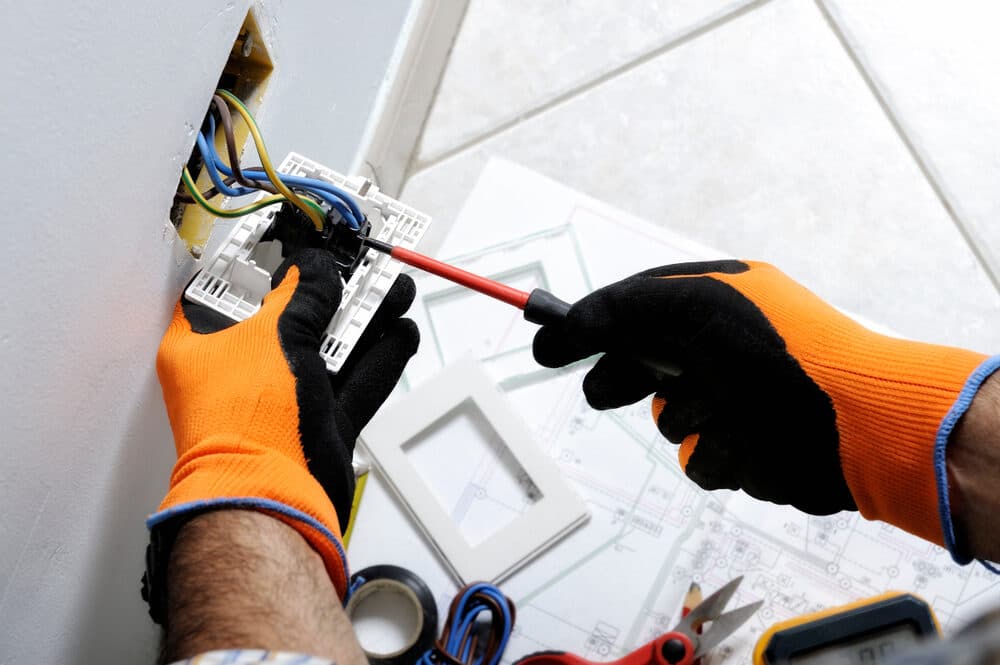 Hands connecting electrical wiring to a wall powerpoint