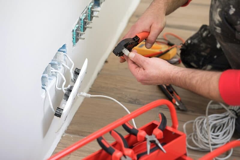 Hands preparing cable beside a row of wall outlets