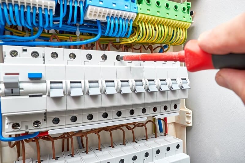 Hands inspecting circuit breakers inside an electrical switchboard