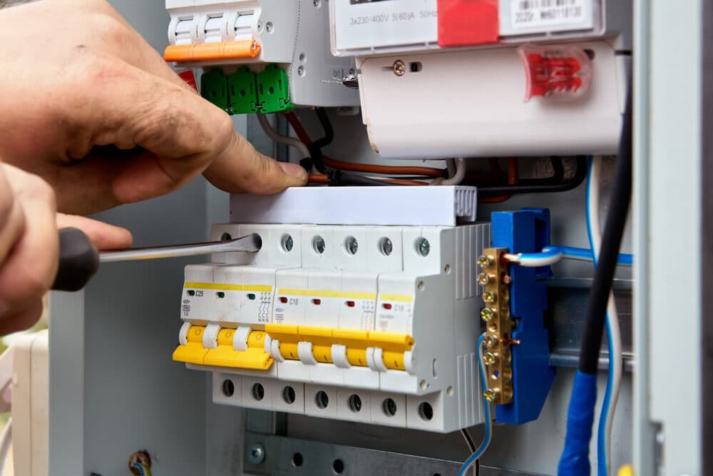 Hand adjusting circuit breakers inside an electrical switchboard